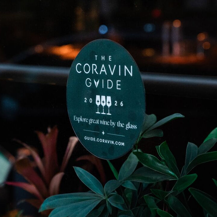 Coravin guide glass distinction sign on a window with blurred building lights in the background